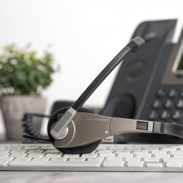 voip service voip phone headset on computer keyboard flower pot in the background